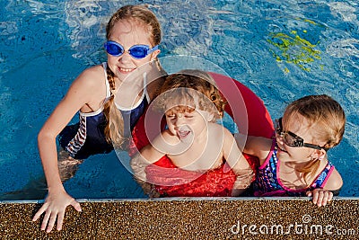 Two little girls and little boy playing in the pool