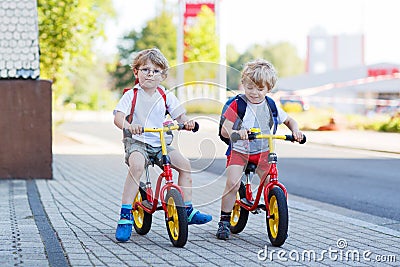 Two little siblings children having fun on bikes in city, outdoo