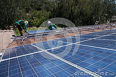 Two male solar workers install solar panels