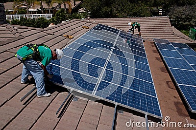 Two male solar workers install solar panels