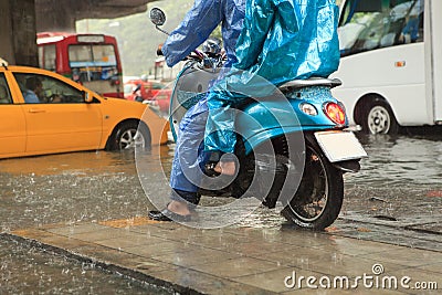 Two man wearing raincoat riding motorcycle