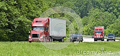 Two Red Semi Trucks On Interstate