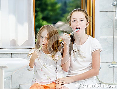 Two sisters cleaning the teeth together