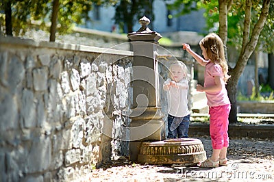 Two sisters playing with drinking water fountain