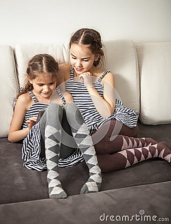 Two sisters using tablet on couch