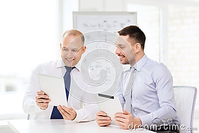 Two smiling businessmen with tablet pc in office