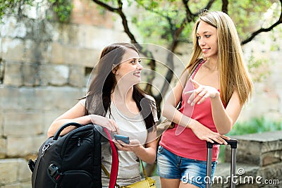 Two smiling girls finding path with smartphone