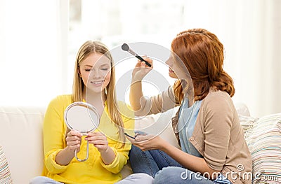 Two smiling teenage girls applying make up at home
