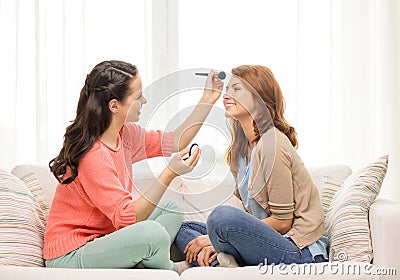 Two smiling teenage girls applying make up at home