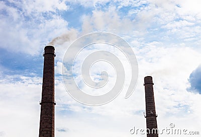 Two smoke stacks of the industrial plant against the cloudy sky