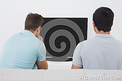 Two soccer fans watching tv