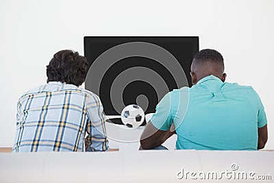 Two soccer fans watching tv