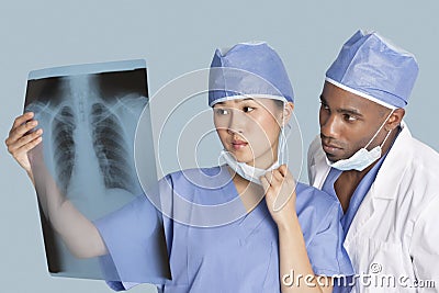 Two surgeons examining x-ray report over light blue background