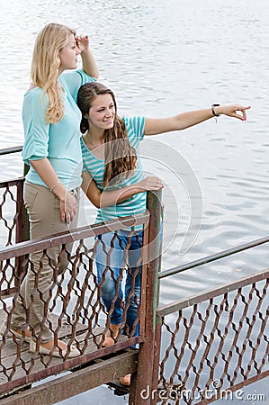 Two Teen Girl Friends looking over water on summer day