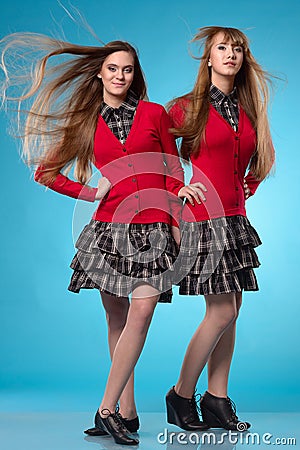 Two teen schoolgirls stand side by side over blue background