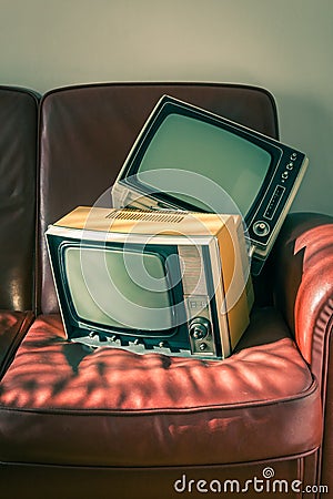 Two vintage televisions on red couch