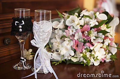 Two wedding glasses and bridal bouquet on table