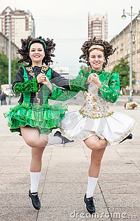 Two women in irish dance dresses and wig dancing