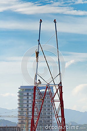 Two workers install a lot of Metal tiered tower.