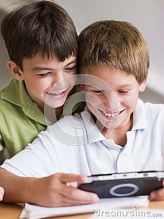 Two Young Boys Playing With A Hand held Video Game