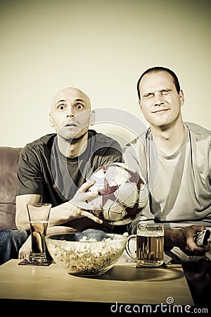 Two young men watching a football match on tv