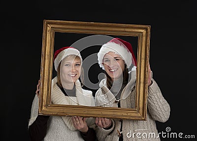 Two young women in a frame, on black