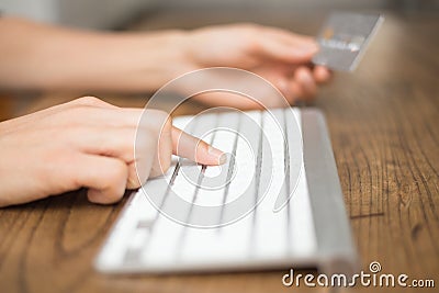 Typing on keyboard and holding credit card for online shopping