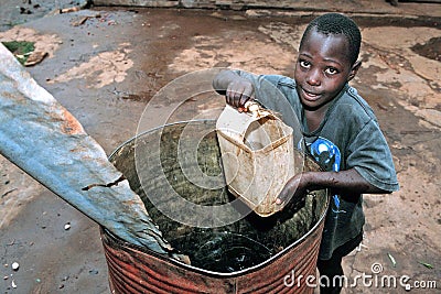 Ugandan boy gets drinking water from rain barrel