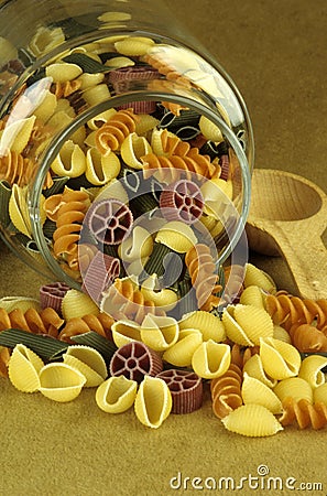 Uncooked pasta spills from glass jar