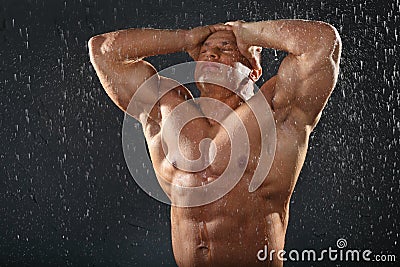 Undressed tanned bodybuilder in rain