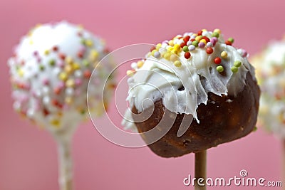 Unfinished cake pops decorated with sprinkles on pink background