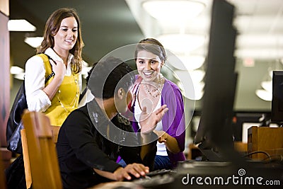 University students conversing by library computer
