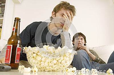 Upset Men Watching TV With Popcorn And Beer On Table