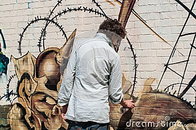 Urban artist drawing graffiti on a wall in Shoreditch.
