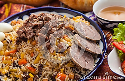 Uzbek national food pilaf on traditional fabric adras