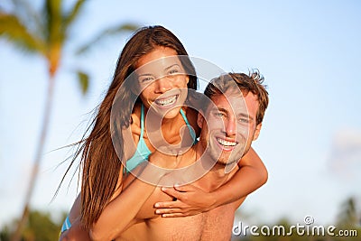 Vacation couple fun on beach, man giving piggyback