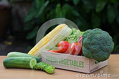 Variety of fresh vegetables in wooden box on wood table