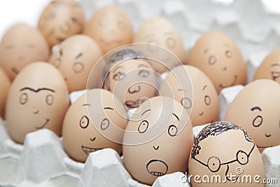 Various facial expressions painted on brown eggs in egg carton