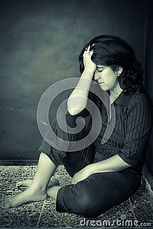 Very depressed woman sitting on a corner