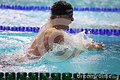 View side of man swims breaststroke in a swimming pool