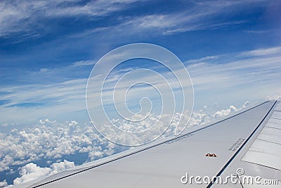 A view though an airplane window where one can see the wing and beautiful cloudy sky