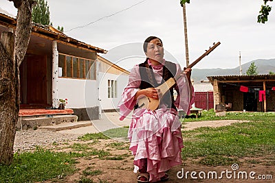 Village woman play on traditional Kyrgyz musical instrument Komuz