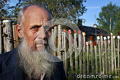 Villager stands behind picket fence on which dried empty tins