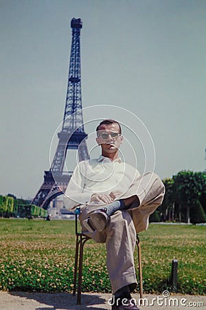 Vintage image of a tourist sitting in front of the Eiffel Tower, Paris, France.