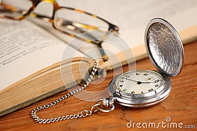 Vintage pocket watch glasses and open old book