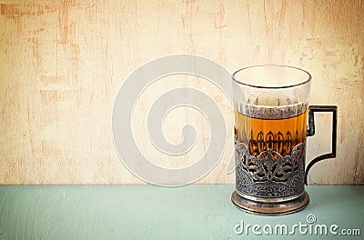 Vintage tea glass-holder over wooden table. retro filtered image