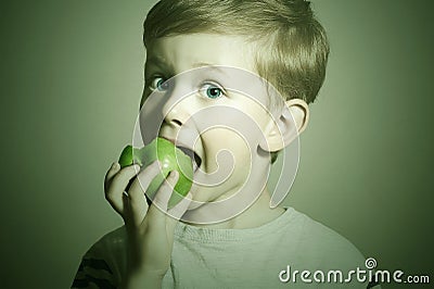 Vitamin.Child eating apple.Little Funny Boy with green apple. Health food. Fruits