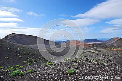 Volcanic mountain landscape in Lanzarote, Canary Islands. Blue sky and clouds in the horizon.