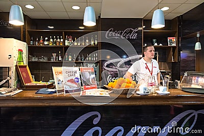 Waiter stands behind bar at Belgrade airport.