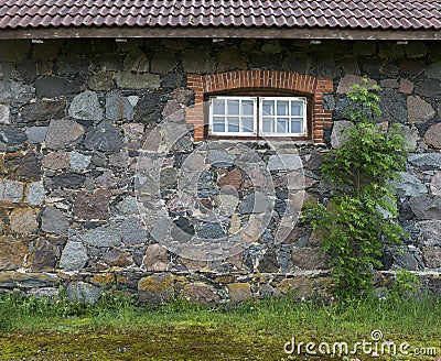 Wall from granite stones with a window and a tree, the old aspha